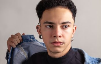 Model Young man with piercings, with curly hair and confident pose wearing a denim jacket